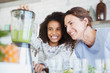 © Sam Edwards/Caia Image - Smiling, enthusiastic mother and daughter making healthy green smoothie in blender in kitchen