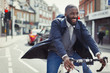 © Caiaimage/Paul Bradbury/Caia Image - Smiling young businessman commuting, riding bicycle on sunny urban street