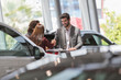 © Martin Barraud/Caia Image - Car salesman handshaking with customers in car dealership showroom