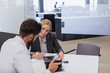 © Martin Barraud/Caia Image - Smiling car saleswoman showing brochure to male customer in car dealership office