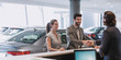 © Martin Barraud/Caia Image - Couple arriving, greeting receptionist handshaking at car dealership showroom