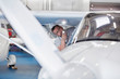 © Agnieszka Olek/Caia Image - Mechanic engineer examining underside of airplane wing flashlight in hangar
