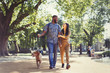 © Paul Bradbury/Caia Image - Happy young couple walking dog in sunny park