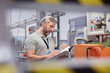 © Agnieszka Olek/Caia Image - Male supervisor clipboard at machinery control panel in fiber optics factory