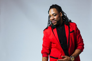 studio portrait of a man wearing a red jacket suit and dreadlocks