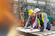 © Rafal Rodzoch/Caia Image - Male engineers reviewing blueprints in factory