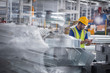 © Martin Barraud/Caia Image - Factory worker with clipboard inspecting steel parts in factory