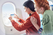 © Caiaimage/Rafal Rodzoch/Caia Image - Young women friends using camera phone at airplane window