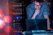 © Agnieszka Olek/Caia Image - Focused male IT technician working at laptop in dark server room