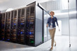 © Rafal Rodzoch/Caia Image - Female IT technician walking in server room