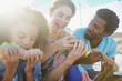 © Sam Edwards/Caia Image - Multi-ethnic family eating baguette sandwiches on sunny beach