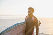 © Sam Edwards/Caia Image - Smiling male surfer walking with surfboard on sunny summer beach