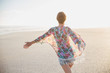 © Sam Edwards/Caia Image - Carefree woman walking with arms outstretched on summer beach