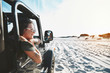 © Trevor Adeline/Caia Image - Smiling young woman leaning out jeep window, enjoying beach road trip