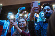 © Sam Edwards/Caia Image - Smiling audience using smart phone flashlights