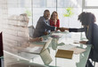 © Caiaimage/Martin Barraud/Caia Image - Businessman businesswoman handshaking across conference table in meeting