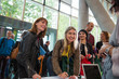 © Sam Edwards/Caia Image - Smiling businesswomen arriving, checking in at conference registration table