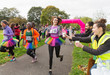 © Chris Ryan/Caia Image - Female runner in tutu reaching for water during charity run in park