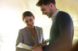 © Caiaimage/Sam Edwards/Caia Image - Smiling businessman and businesswoman discussing paperwork