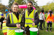 © Chris Ryan/Caia Image - Portrait smiling volunteers donation buckets at charity run in park