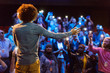 © Martin Barraud/Caia Image - Speaker on stage talking to audience with smart phone flashlights
