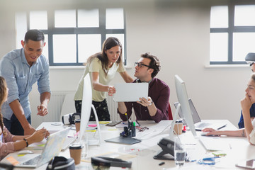 Designers working at computers and laptops in open plan office