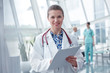 © Rafal Rodzoch/Caia Image - Portrait smiling, confident female doctor with clipboard in hospital