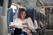 © Agnieszka Olek/Caia Image - Businesswoman working listening to music headphones smart phone on passenger train