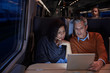 © Agnieszka Olek/Caia Image - Couple using digital tablet on dark passenger train at night