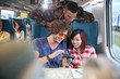 © Agnieszka Olek/Caia Image - Young friends looking at photographs on digital camera on passenger train
