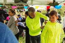 Father Pinning Marathon Bib On Son At Charity Run In Park Tent
