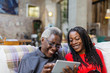 © Sam Edwards/Caia Image - Adult daughter teaching senior father how to use digital tablet on sofa