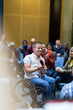 © Martin Barraud/Caia Image - Smiling woman in wheelchair speaking with microphone in audience