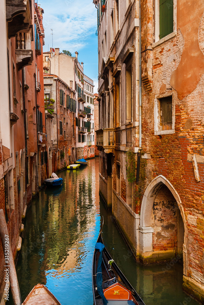 View of a characteristic Venice narrow canal with gondola and old traditional houses in the Castello District - obrazy, fototapety, plakaty 