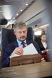 © Rafal Rodzoch/Caia Image - Businessman removing laptop from briefcase on passenger train