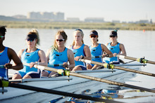 Female Rowers Rowing Scull On Sunny Lake