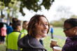 © Sam Edwards/Caia Image - Portrait smiling female runner resting, drinking water at charity run in park