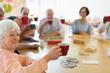 © Martin Barraud/Caia Image - Portrait happy senior woman enjoying afternoon tea friends in community center