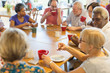 © Martin Barraud/Caia Image - Friends drinking tea and playing games at table in community center