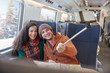 © Agnieszka Olek/Caia Image - Happy young couple taking selfie with selfie stick on passenger train