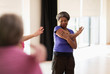 © Martin Barraud/Caia Image - Smiling active senior stretching arm in exercise class