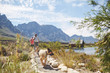 © Trevor Adeline/Caia Image - Hikers and dogs walking on footpath along sunny summer lake
