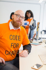 Portrait confident hacker coding for charity at hackathon