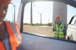 © Trevor Adeline/Caia Image - Smiling engineer using walkie-talkie at truck at sunny wind turbine power plant