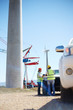 © Trevor Adeline/Caia Image - Engineers meeting at truck at sunny wind turbine power plant