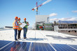 © Trevor Adeline/Caia Image - Engineers with blueprint at solar panels at sunny power plant