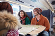 © Agnieszka Olek/Caia Image - Smiling young friends planning with map on passenger train