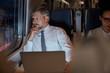 © Agnieszka Olek/Caia Image - Serious, thoughtful businessman working at laptop, looking out window on passenger train at night