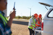 © Trevor Adeline/Caia Image - Engineers reviewing blueprints at truck at sunny wind turbine power plant