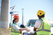© Trevor Adeline/Caia Image - Engineers reviewing blueprints at truck at sunny wind turbine power plant